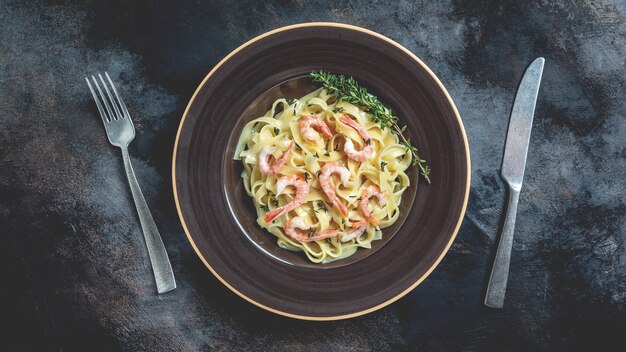 Tagliatelles aux crevettes, sauce béchamel et thym. Fettuccine de pâtes italiennes. bannière, lieu de recette de menu pour le texte, vue de dessus.