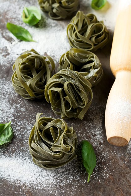 Tagliatelles de pâtes crues sur une surface sombre. Mise au point sélective.