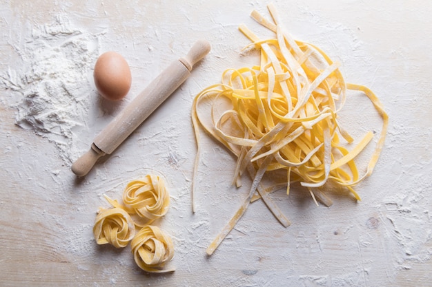 Tagliatelles de pâtes fraîches italiennes faites maison à une table en bois. Pâtes italiennes à base de farine, d'eau et d'œufs.