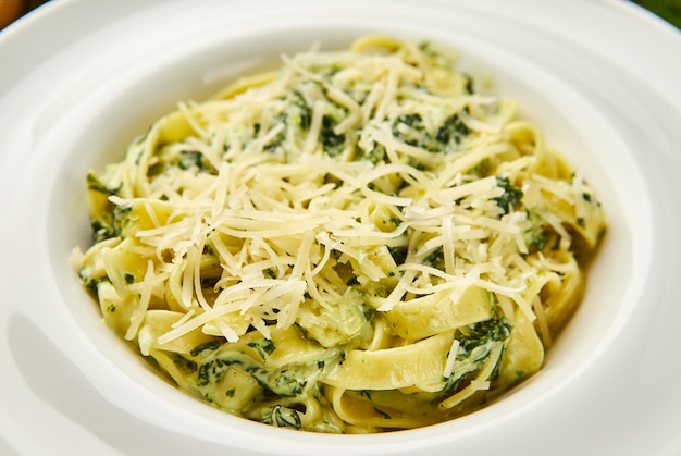 Tagliatelles de pâtes italiennes traditionnelles aux épinards, fromage parmesan à pâte dure et sauce à la crème