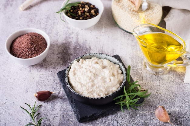 Tahini au sésame avec sel noir dans un bol et ingrédients de cuisine sur la table