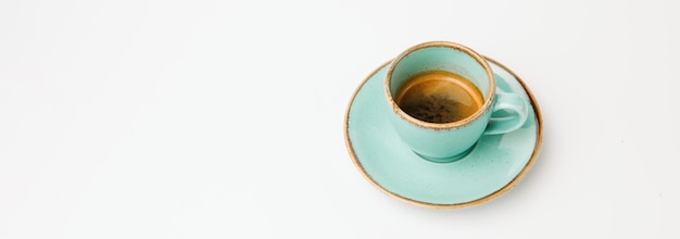 Taille de la bannière isolée sur un coup blanc d'une tasse et d'une soucoupe turquoise d'espresso