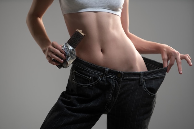Taille maigre Femme mince en jeans surdimensionnés concept de perte de poids Régime alimentaire régime au chocolat