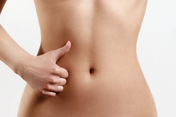 Photo taille mince et athlétique d'une jeune femme. la main au premier plan montre un geste du doigt vers le haut. le concept de la beauté et de la santé des femmes, de la nutrition et de l'alimentation, belle figure