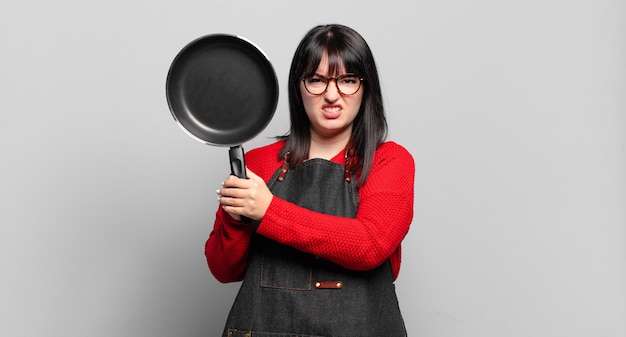 Taille plus jolie femme chef cuisinant avec une casserole