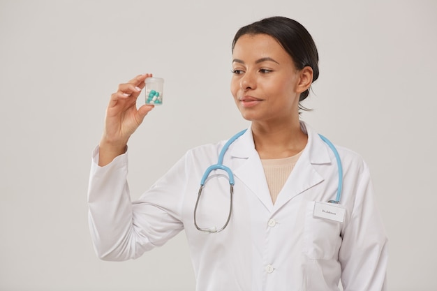 Taille portrait de belle femme médecin tenant une bouteille de pilules