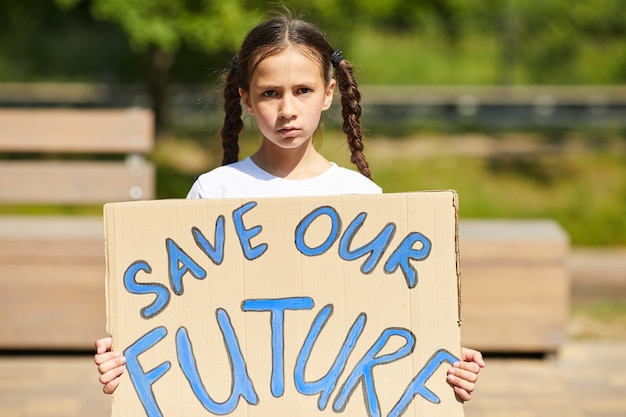 Taille portrait of cute girl holding sign avec SAVE FUTURE écrit tout en protestant pour la nature et l'économie à l'extérieur