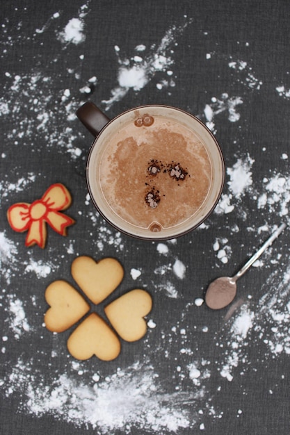 Photo taille de table noire avec de la farine tasse de chocolat chaud avec des morceaux de biscuits et cuillère avec du cacao noël