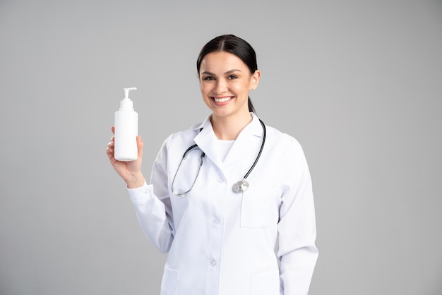 Taille vue portrait de l'infirmière ou du médecin portant une robe de protection tenant une bouteille avec un désinfectant à la main. Stock photo