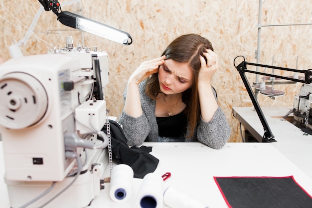 Tailleur fatigué assis sur son lieu de travail avec des maux de tête.