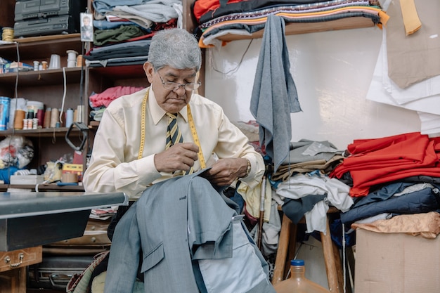 Tailleur mexicain âgé cousant à la main sur des entreprises locales