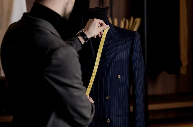 Le tailleur prend des mesures à partir d'un atelier de couture de travail fait main de costume d'affaires