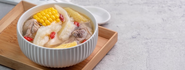 Taïwanais maison délicieuse soupe au poulet dans un bol avec de l'ananas, de la courge amère et du maïs sucré sur table gris ciment