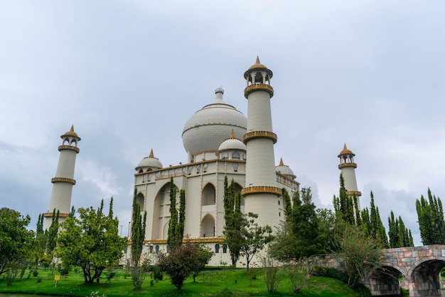 Photo un taj mahal blanc et beige avec une pelouse verte et des arbres devant lui.