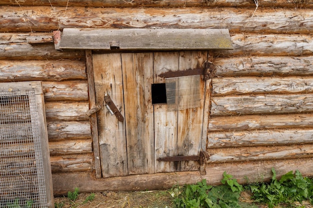 Étal d'animaux. Porte fermée dans une grange en bois. Entrée de l'abri pour animaux.