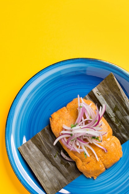 Tamale péruvien, petit déjeuner typiquement péruvien. Fabriqué à partir de maïs et farci au poulet et servi avec une salade d'oignons violets.