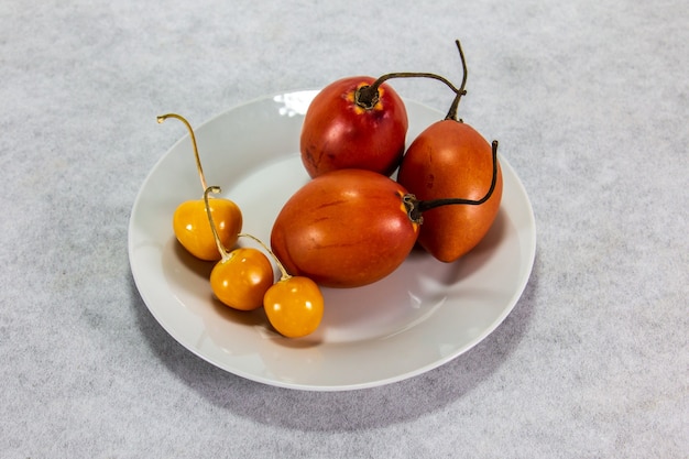 tamarillo ou arbre tomate sur planche de bois à côté d'uvilla ou d'aguaymanto physalis
