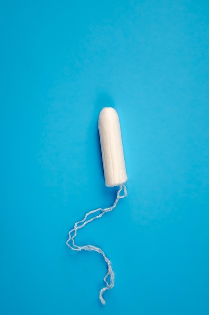 Un tampon féminin hygiénique sur fond bleu. tampon pour femme, protection pendant la menstruation.