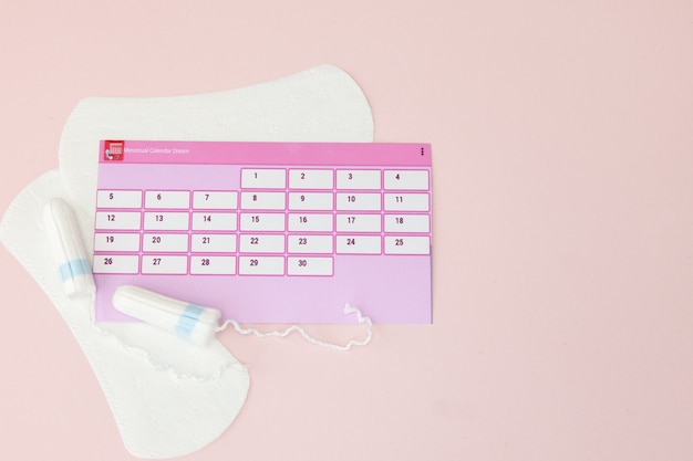 Tampon, féminin, serviettes hygiéniques pour les jours critiques, calendrier féminin, analgésiques pendant la menstruation sur fond rose. Suivi du cycle menstruel et de l'ovulation.