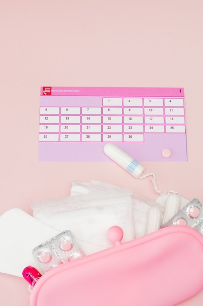 Tampon, féminin, serviettes hygiéniques pour les jours critiques, calendrier féminin, analgésiques pendant les menstruations sur un mur rose. Suivi du cycle menstruel et de l'ovulation