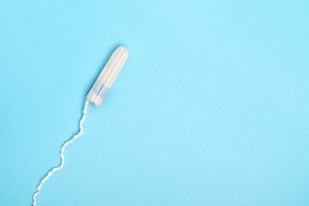 Tampon menstruel jetable sur fond bleu. Cycle menstruel. Hygiène et protection. PMS, jours critiques, cycle menstruel, concept de santé féminine