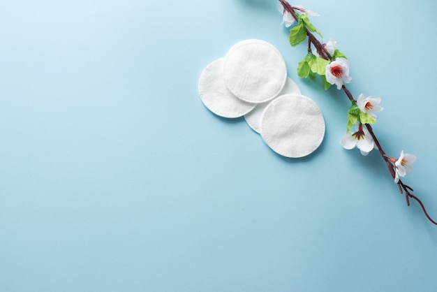 Tampons de coton pour le démaquillage avec des fleurs blanches sur le fond bleu