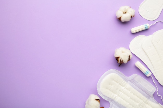 Tampons menstruels et serviettes en coton sur fond violet. Cycle menstruel. Hygiène et protection. Vue de dessus.