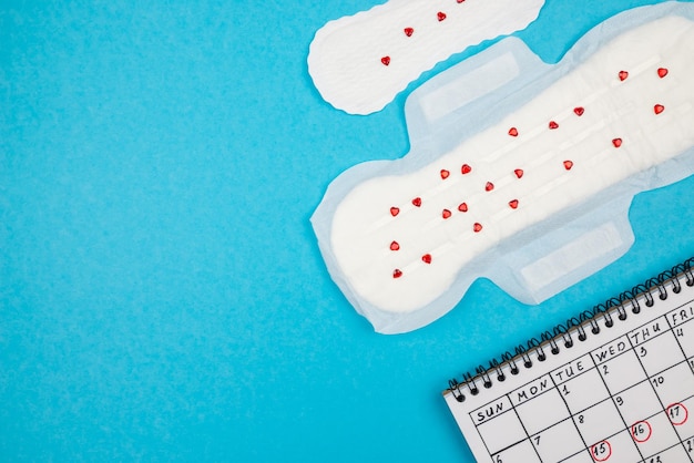 Tampons pour femmes avec des confettis et un calendrier avec des marques sur fond bleu avec espace de copie