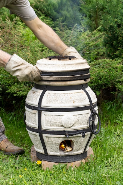 Le tandoor brûlant de l'argile se dresse sur l'herbe De la fumée en sort