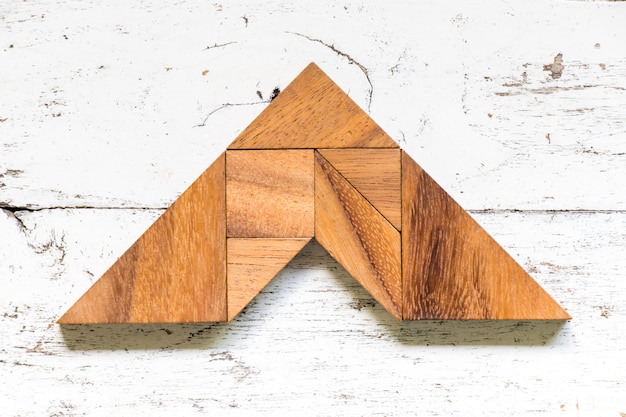 Tangram puzzle en forme de flèche sur le vieux fond de bois blanc