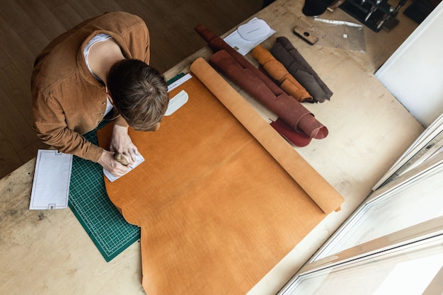 Tanneur masculin faisant un schéma de coupe de sac travaillant à l'atelier de cuir création artisanale