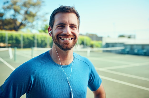 En tant qu'athlète, la forme physique vient toujours en premier Portrait d'un jeune homme sportif écoutant de la musique tout en faisant de l'exercice sur un court de tennis