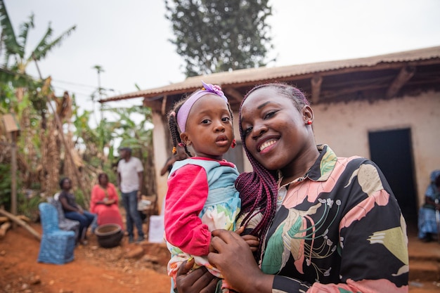 Tante tient sa nièce dans ses bras alors qu'ils sont dans un village africain