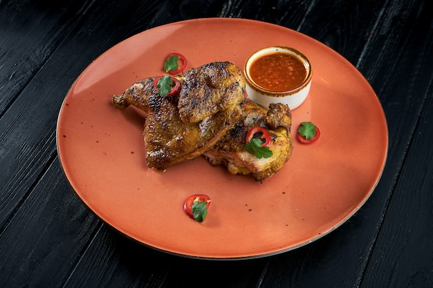 Tapaka de poulet sur une assiette, sur fond de bois. Poulet grillé.