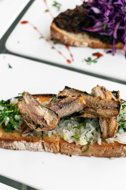 Tapas portugais de sandwich à pain grillé ouvert avec sardine et ail à l'oignon