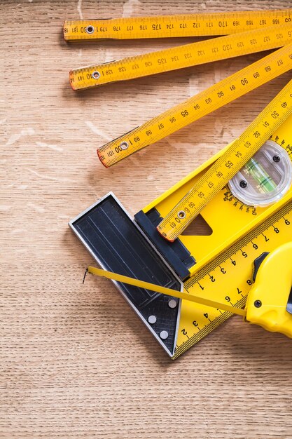 Tape de mesure en bois, niveau de construction et règle carrée sur planche en bois de chêne