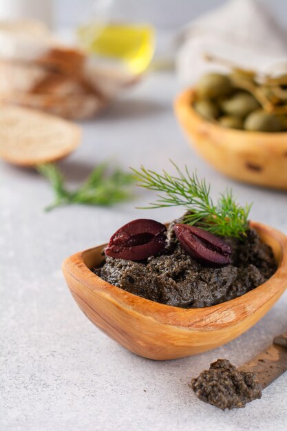 Tapenade noire ou tapas, plat traditionnel provençal ou trempette aux olives et basilic sur fond de table en bois ancien. Mise au point sélective. Vue de dessus