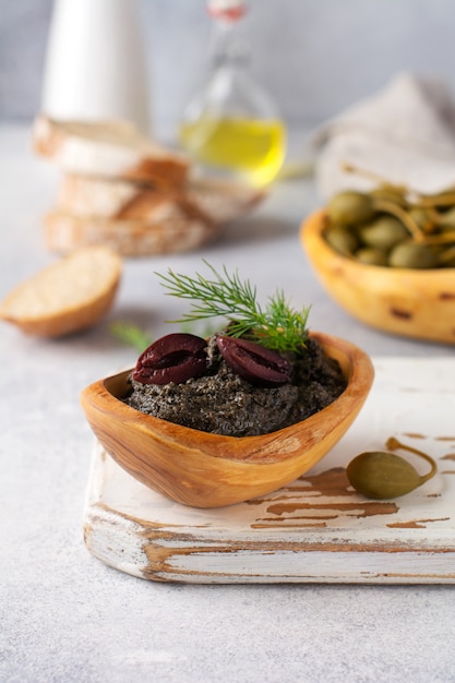 Tapenade noire ou tapas, plat traditionnel provençal ou trempette aux olives et basilic sur fond de table en bois ancien. Mise au point sélective. Vue de dessus