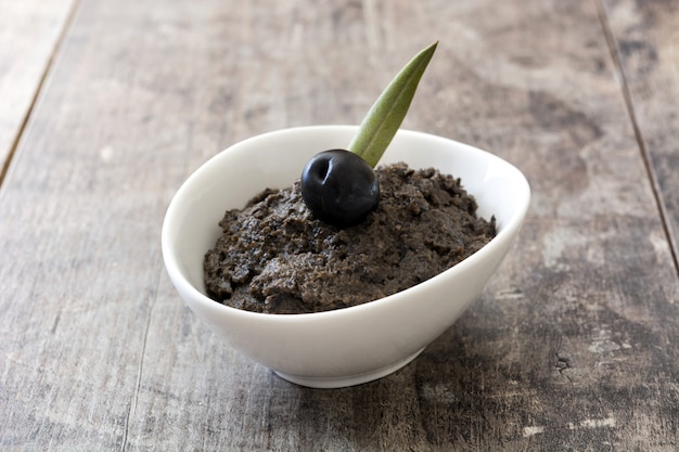 Tapenade d'olives noires aux anchois, ail et huile d'olive sur table en bois