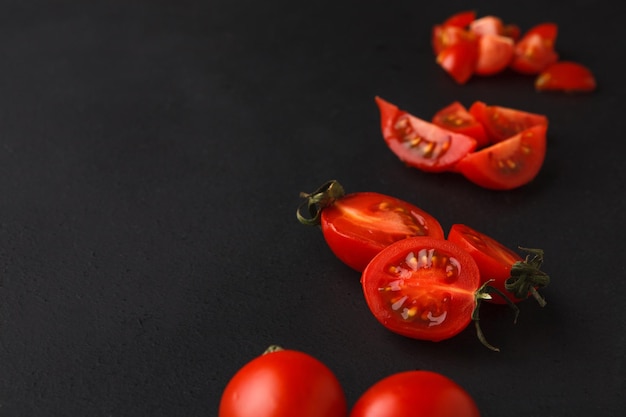 Étapes de la coupe des tomates sur fond noir. Couper des légumes frais, cuisiner des aliments sains.