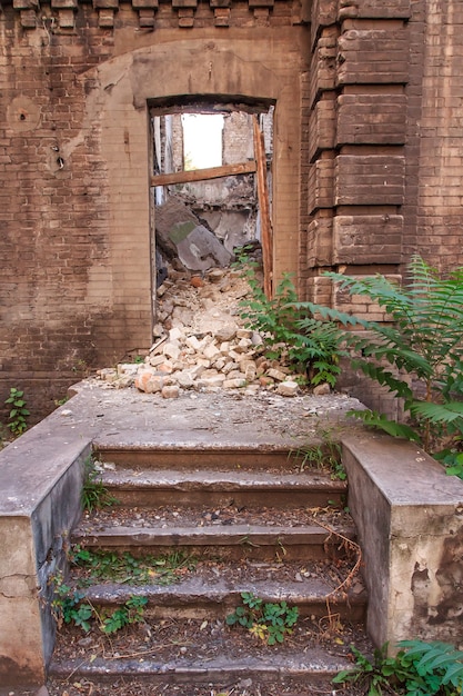 Étapes devant l'entrée dans le vieux bâtiment en brique abandonné avec des murs en ruine à l'intérieur