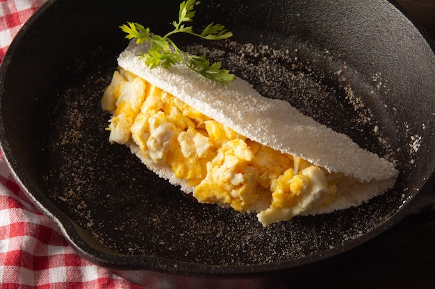 Photo tapioca pancake avec des œufs nourriture de manioc brésilien en haut vue avant à l'intérieur de la casserole en acier