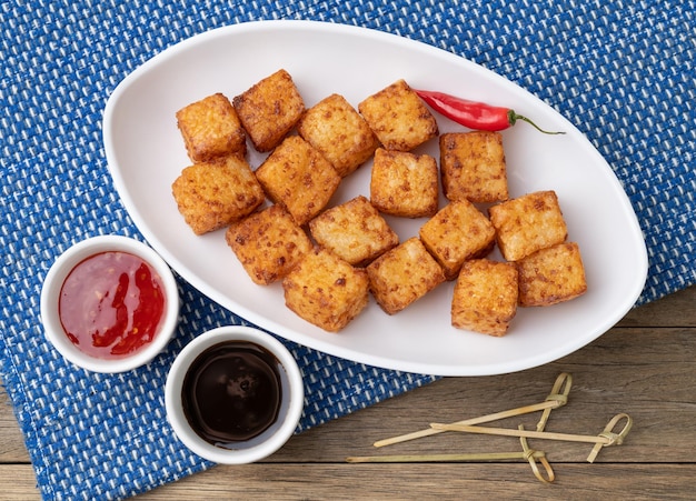 Photo dés de tapioca typique du nord-est de la cuisine brésilienne avec du piment et du sirop de sucre sur une table en bois