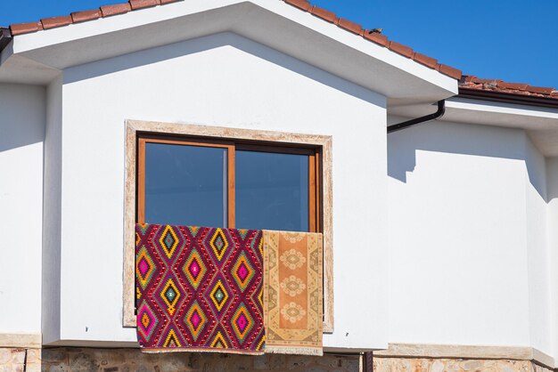 Photo des tapis aux ornements orientaux sont séchés sur la fenêtre d'une maison blanche comme neige en turquie