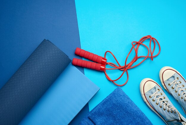 Tapis Bleu Torsadé, Une Paire De Chaussures De Sport Bleues Et Une Corde à Sauter Rouge