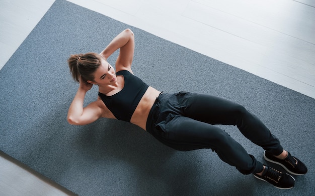 Sur le tapis. Faire des abdos au sol dans la salle de gym. Femme belle remise en forme féminine.