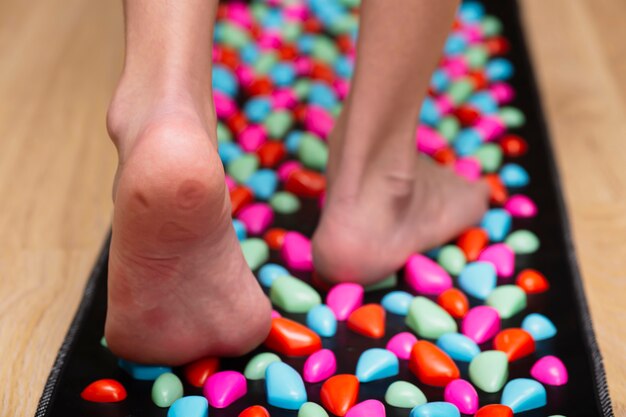 Tapis de massage avec des pierres pour le gros plan de la jambe du pied avec des points de pression des pierres