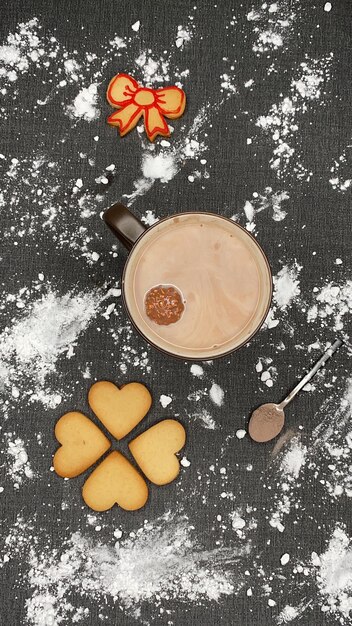 Photo tapis de table noir avec de la farine une tasse de chocolat chaud avec des biscuits de chocolat flottants et une cuillère de cacao