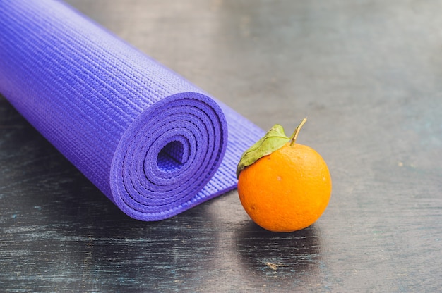 Tapis de yoga et orange sur fond de bois