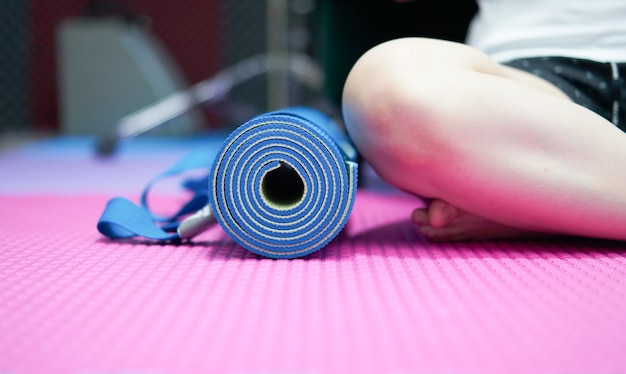 Tapis de yoga sur le sol à côté de s'asseoir jambes croisées s'accroupir sur le sol intérieur maison en vêtements de sport